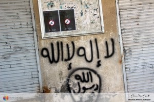 Dieses Kampagnenplakat findet sich im Moment in vielen Städten und Dörfern und Syriens – in diesem Fall über einem Graffiti der Organisation „Islamischer Staat”. Foto: Development Interaction Network.