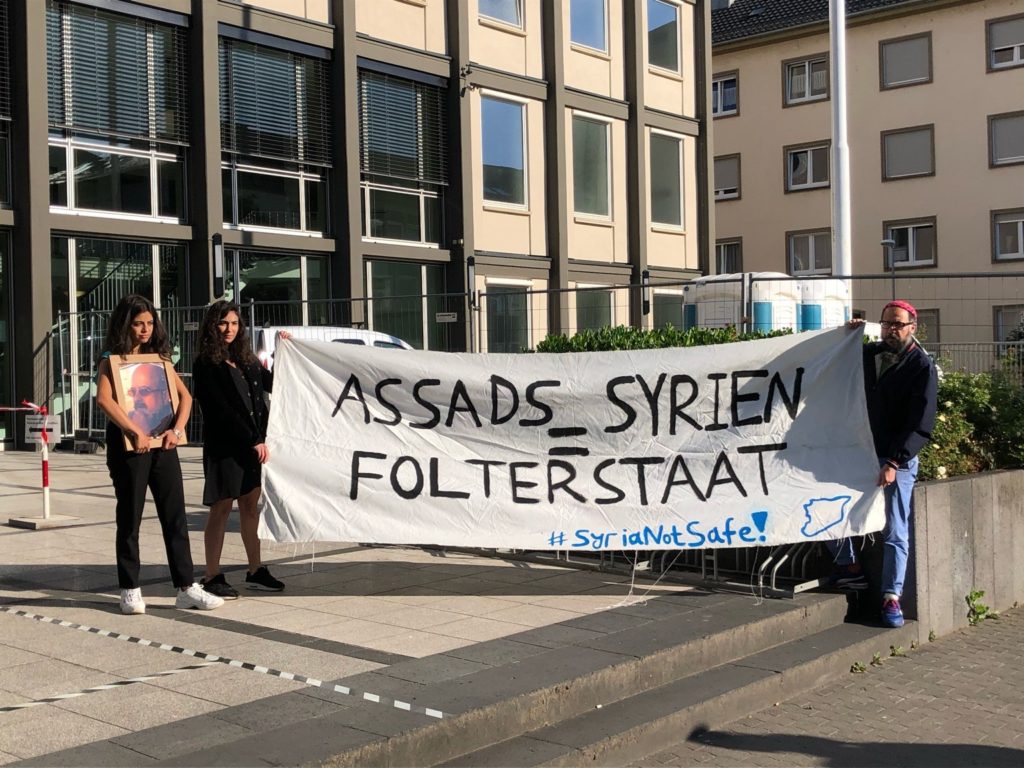 Während dem Folterprozess in Koblenz machen Aktivist*innen der #SyriaNotSafe-Kampagne darauf aufmerksam, dass die Folter in Syrien andauert und niemand dorthin abgeschoben werden darf.